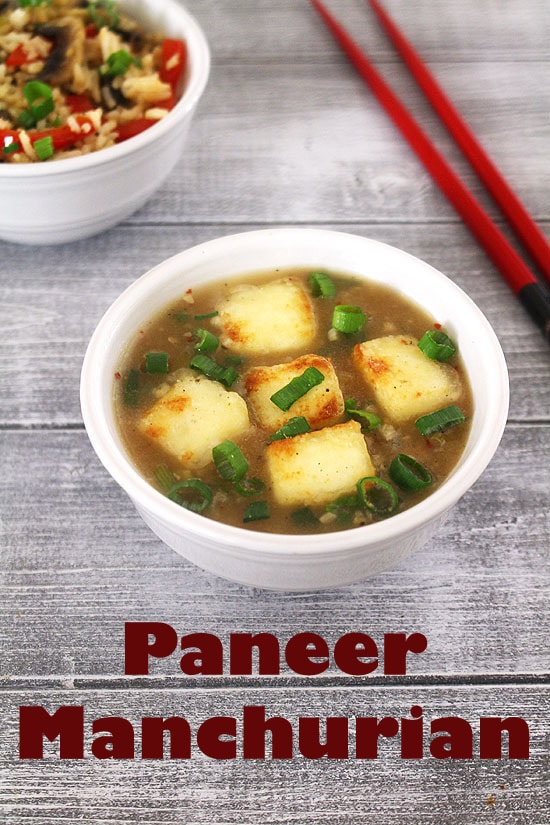 Paneer manchurian garnished with spring onion greens with chopsticks on the sides.
