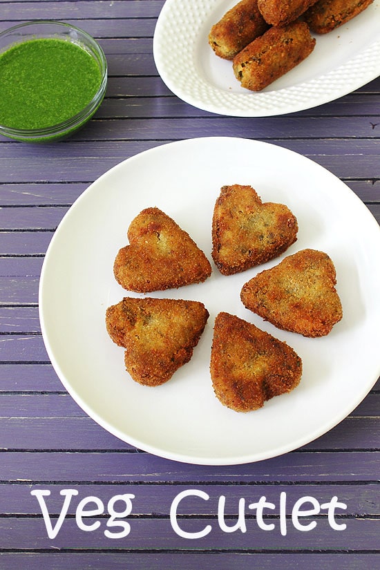 Heart shaped veg cutlet in a plate with green chutney in the back.