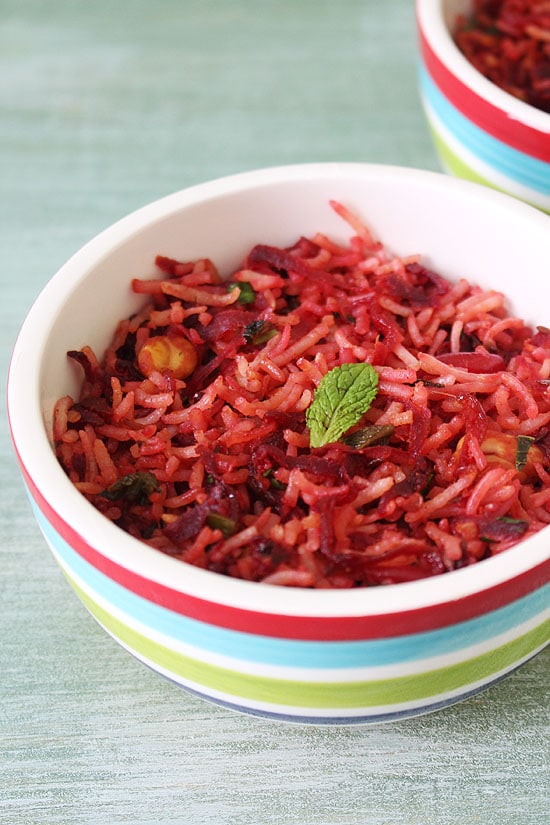 Beetroot rice in a bowl with a garnish of mint leaf.