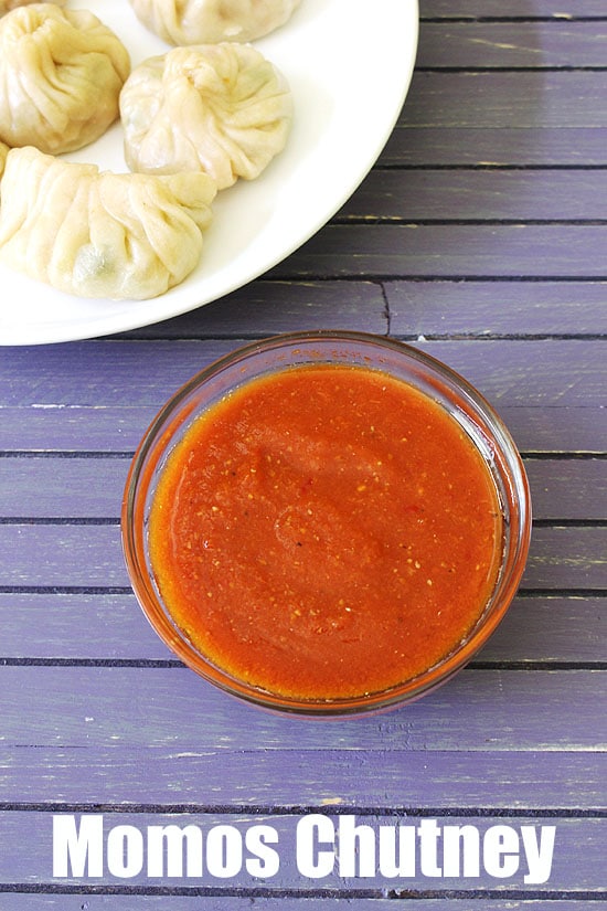 Momos chutney in a bowl with a plate of momos.