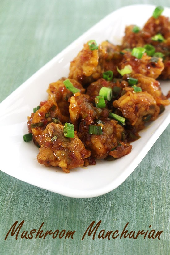 Mushroom manchurian in a plate and garnished with spring onion greens.