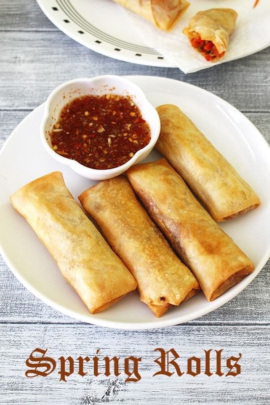 4 spring rolls in a plate with a dipping sauce.