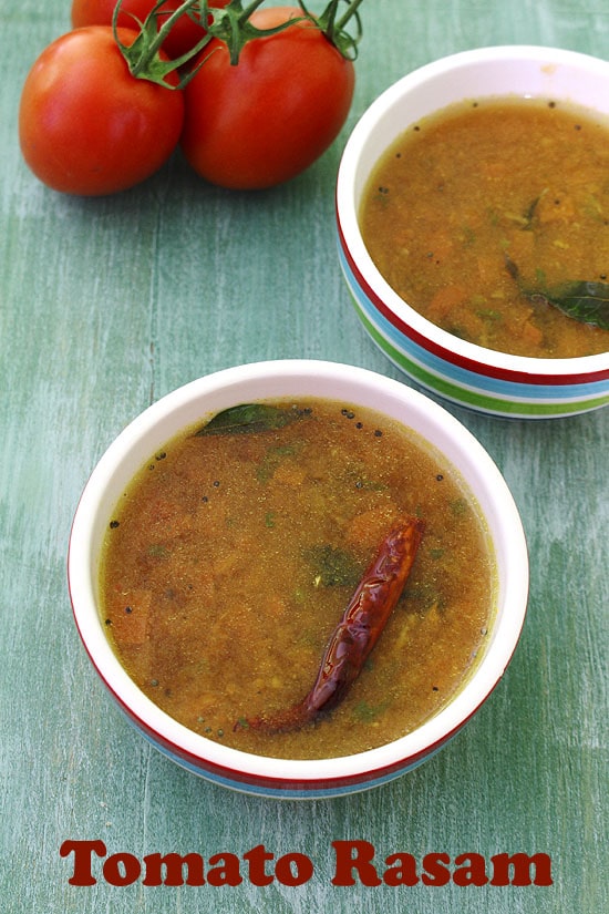 2 bowls of tomato rasam with tomatoes in the back.