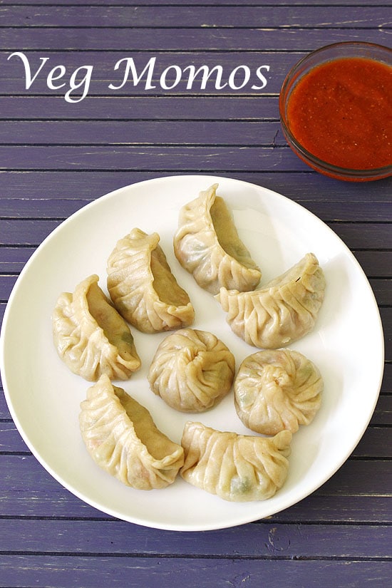 Momos served in a plate with momo sauce in the back.