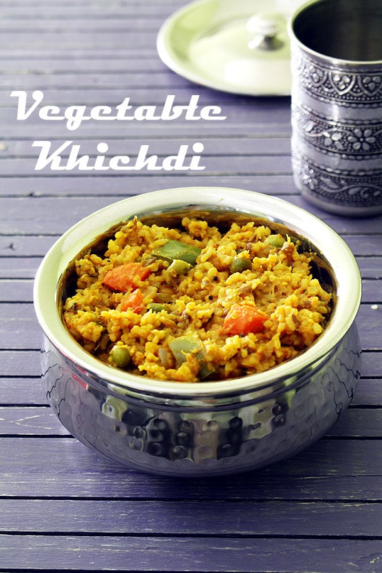 Vegetable khichdi in a serving handi with a glass and lid in the back.