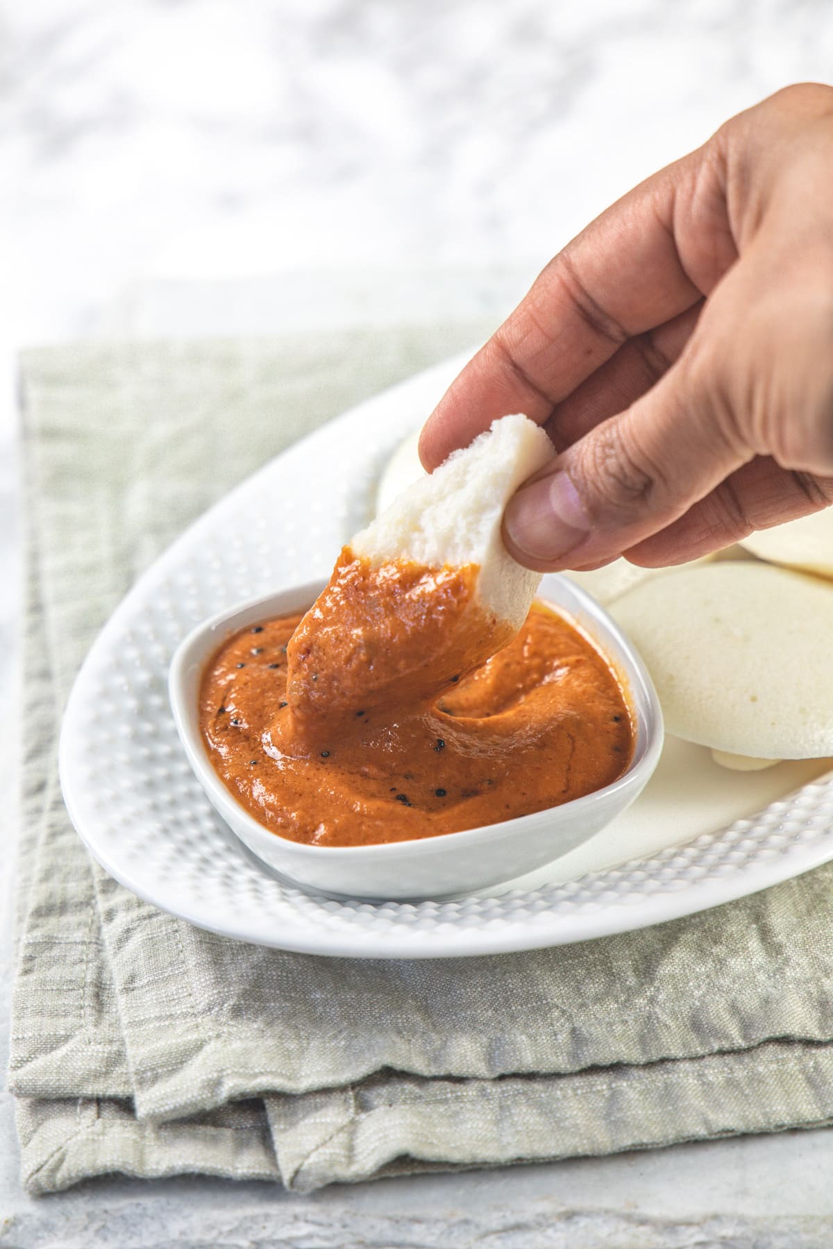 Idli dipped in tomato chutney.