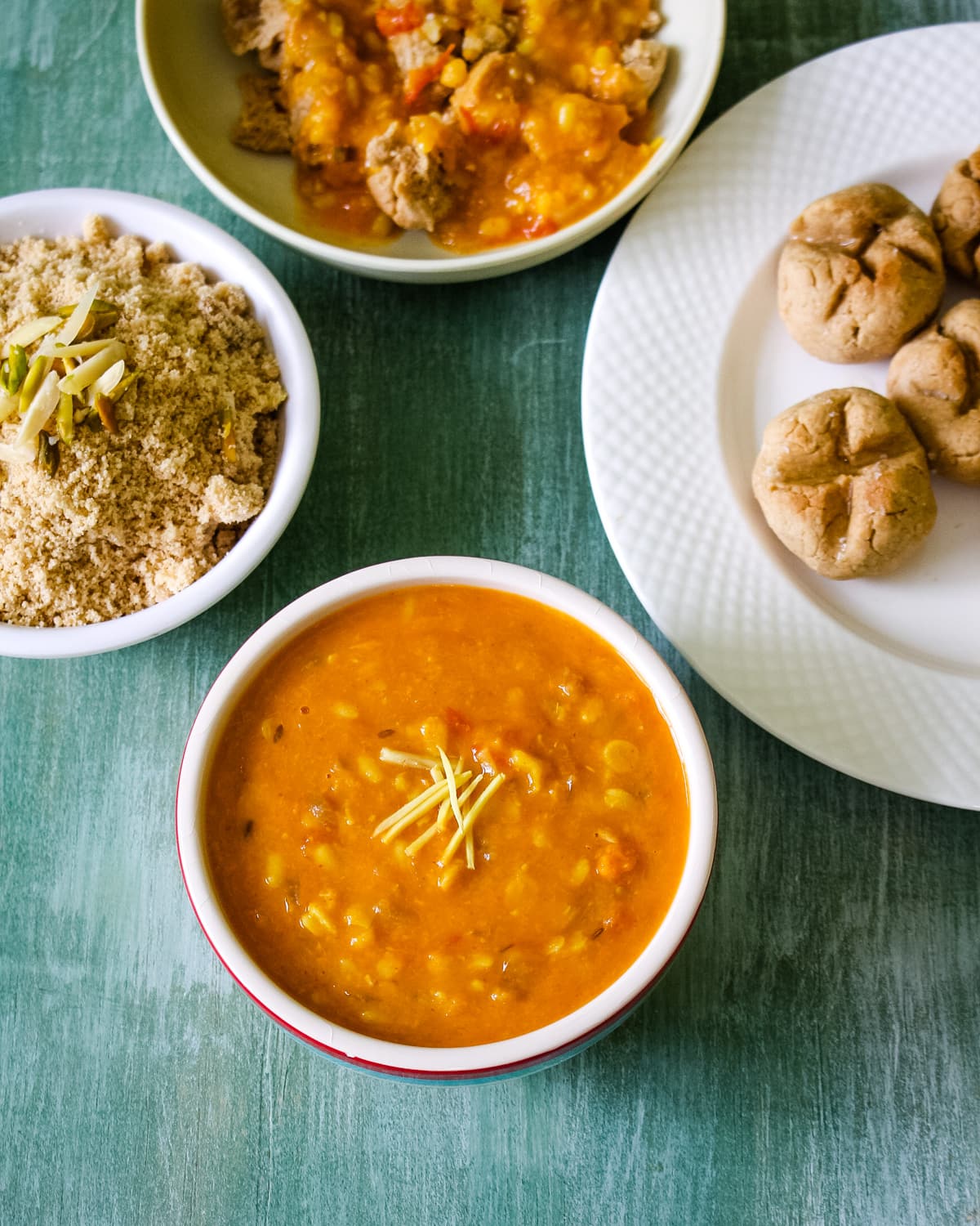 A bowl of panchmel dal garnished with ginger and churma, bati, dal bati on the side.