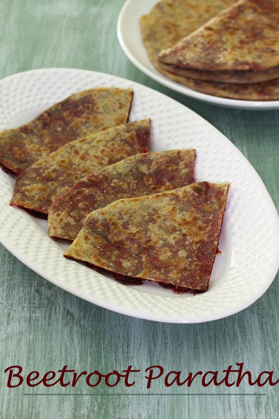Beetroot paratha triangles served in an oval plate.