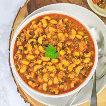 Black eyed peas curry in a bowl garnished with cilantro and 2 spoons on the side.