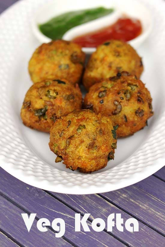 Vegetable kofta in an oval plate with ketchup and coriander chutney.