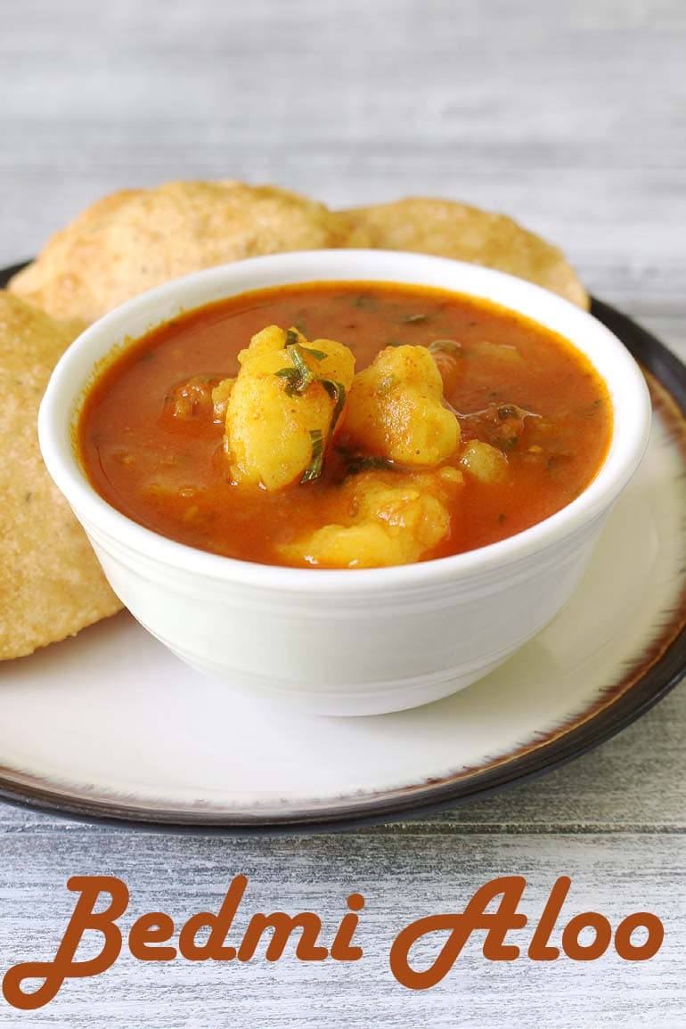 Bedmi aloo sabzi served in a bowl with bedmi puri on the side.