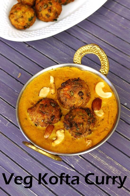 Veg kofta curry served in a serving kadai, garnished with cashew, almonds and few kofta in a plate in the back.