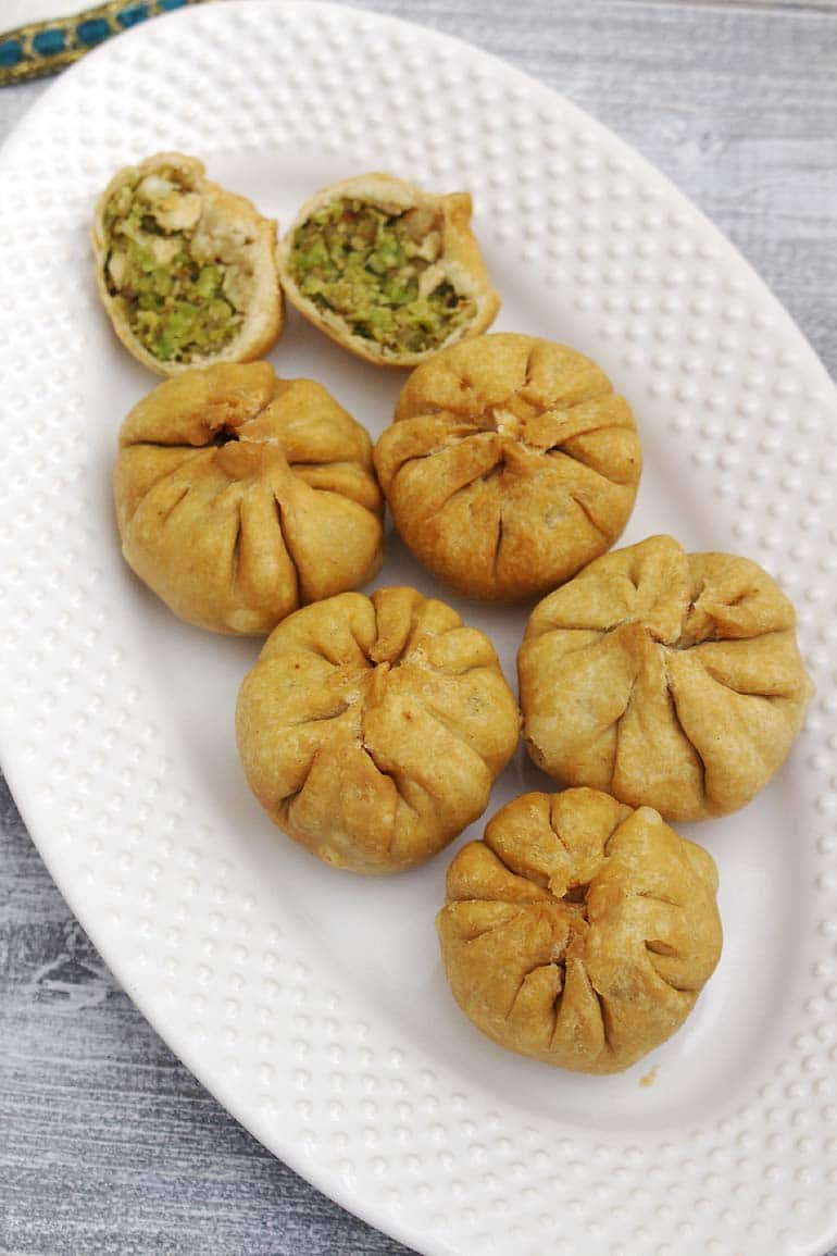 Lilva kachori served in a plate with one cut open in half.