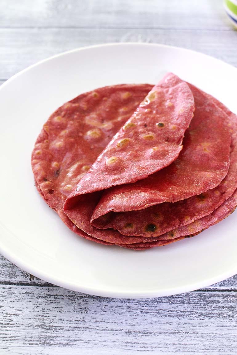 Beetroot roti served in a plate with first 2 rotis are folded in half.