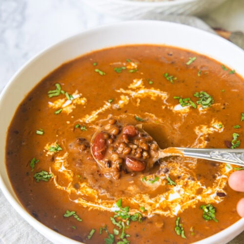 Taking a spoonful of dal makhani from a bowl.