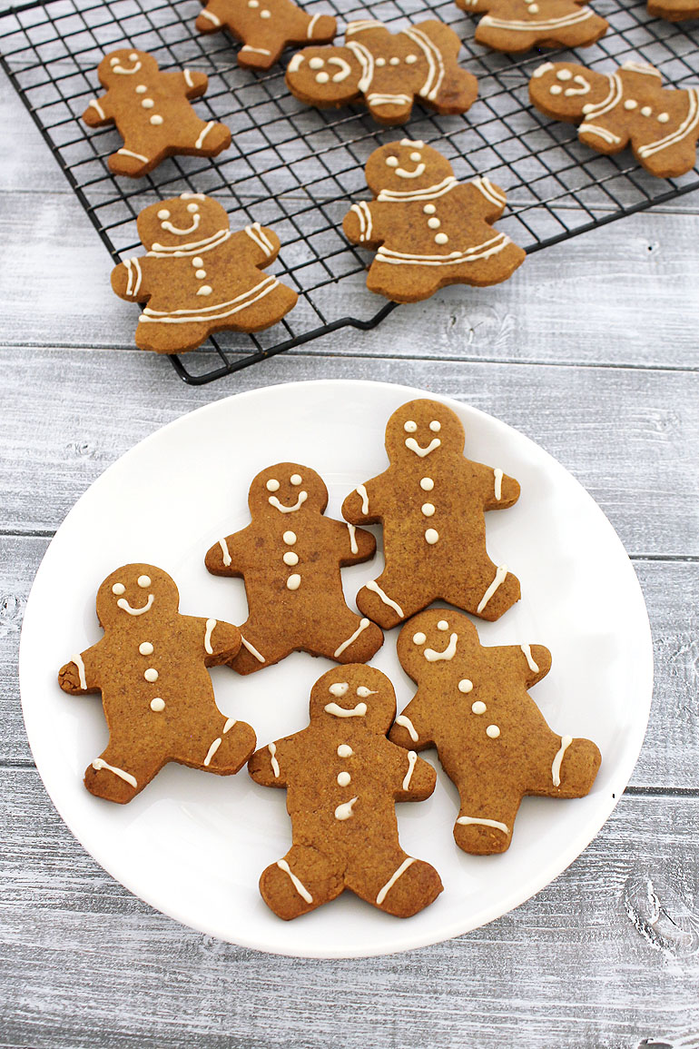 Eggless gingerbread men cookies in a plate and a few more on a cooling rack in the back.