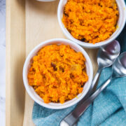 3 bowls of carrot halwa in a tray with spoons.