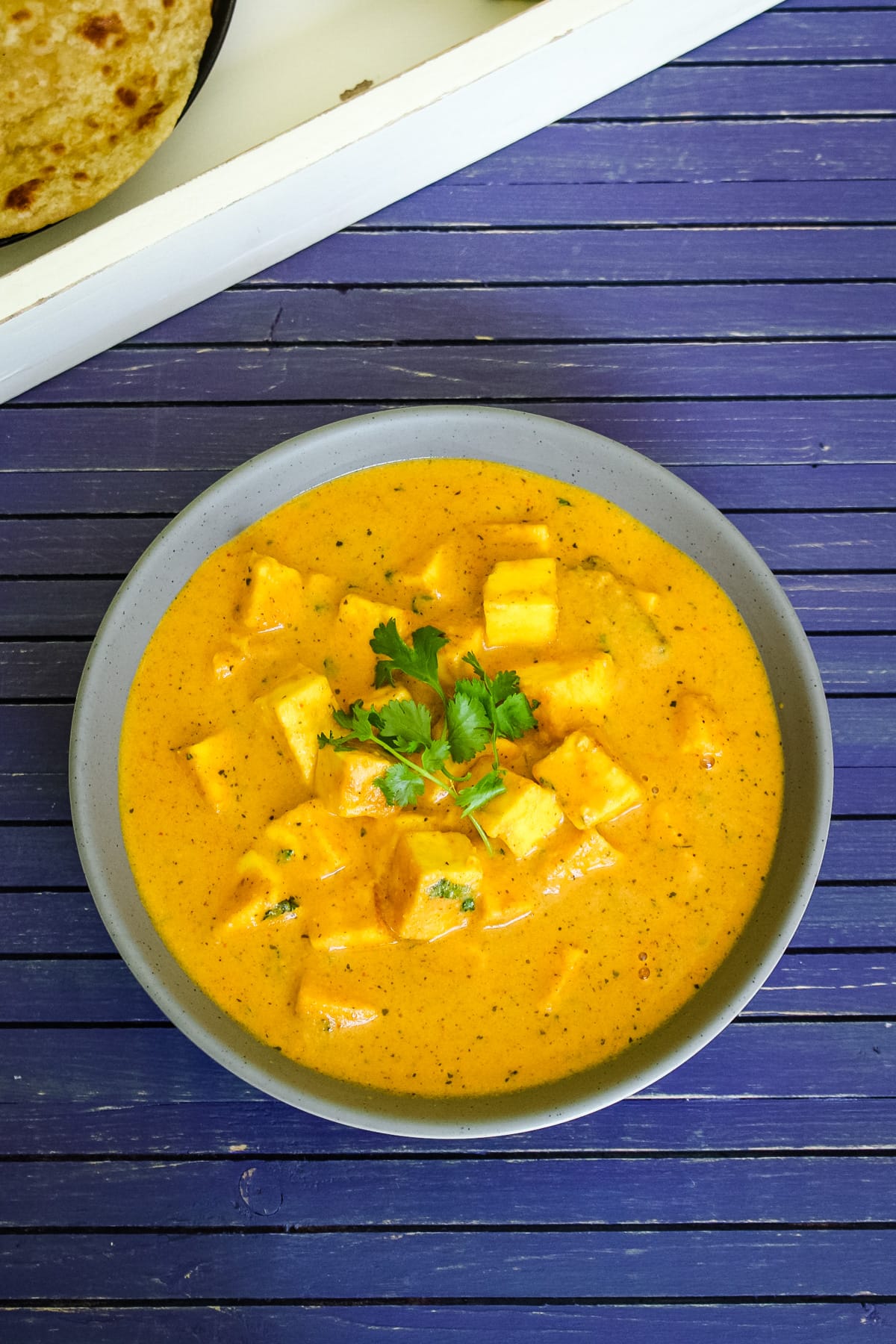 Top view of paneer butter masala in a bowl with cilantro leaves.
