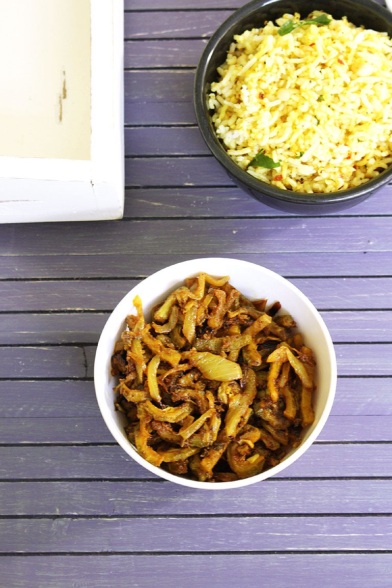 karela sabzi in a bowl and rice bowl in the back.