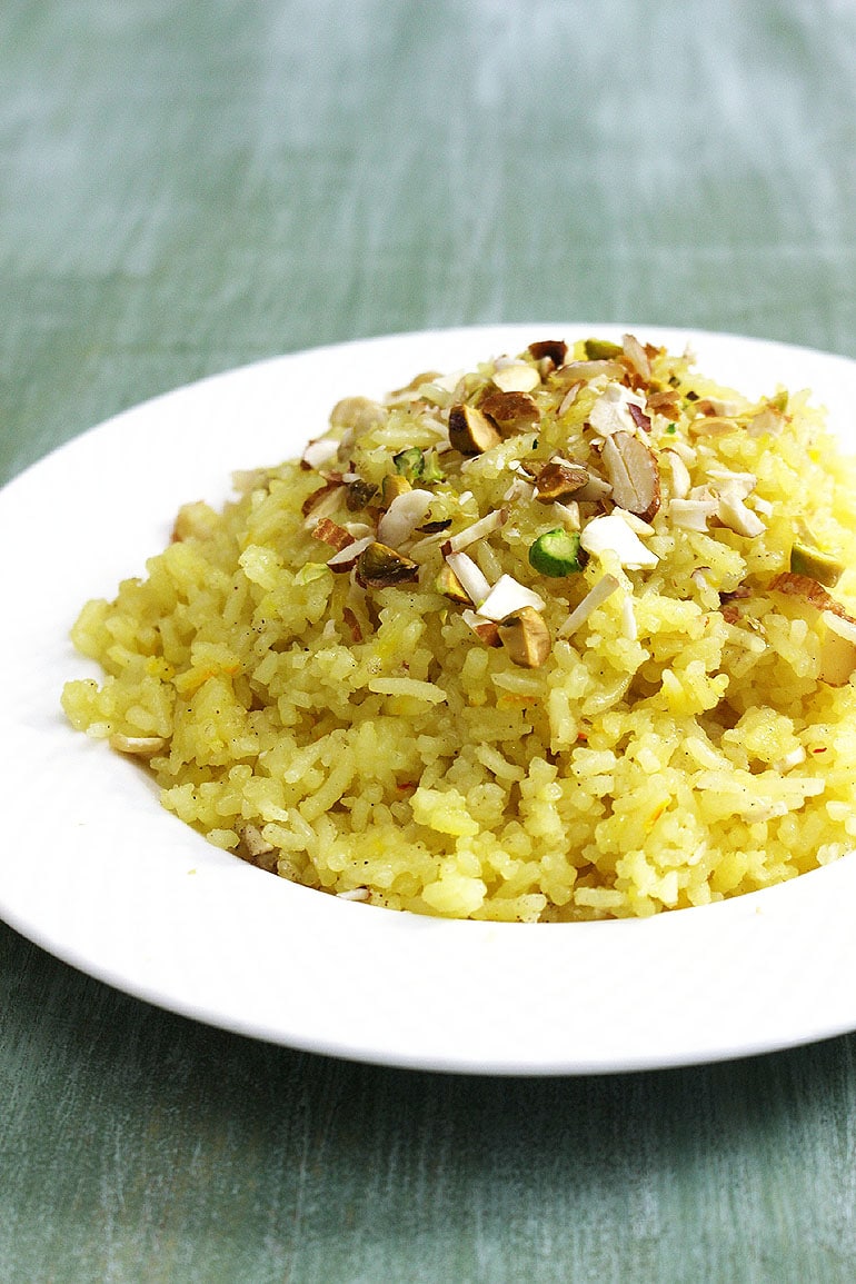 Meethe chawal served in a plate and garnished with chopped nuts.