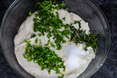 adding salt, green chilies, cilantro and curry leaves to the batter
