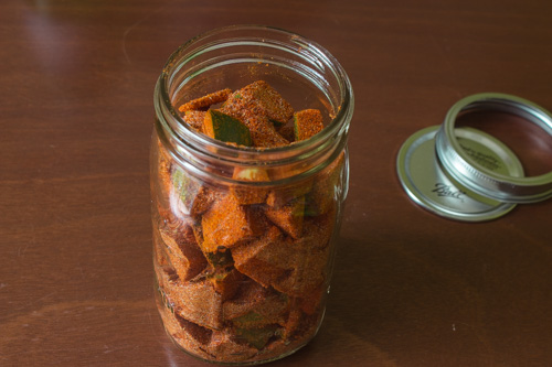 spices coated mangoes added into the glass jar