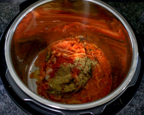 adding spice powders to cooked tomatoes