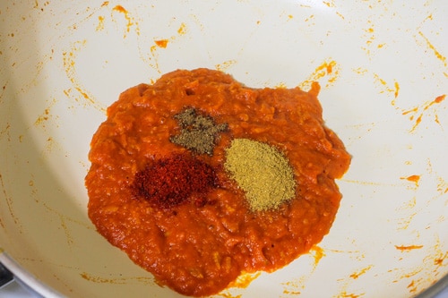 adding spices to cooked tomato puree