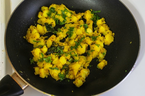 Sprinkling chopped cilantro leaves on aloo bhaji