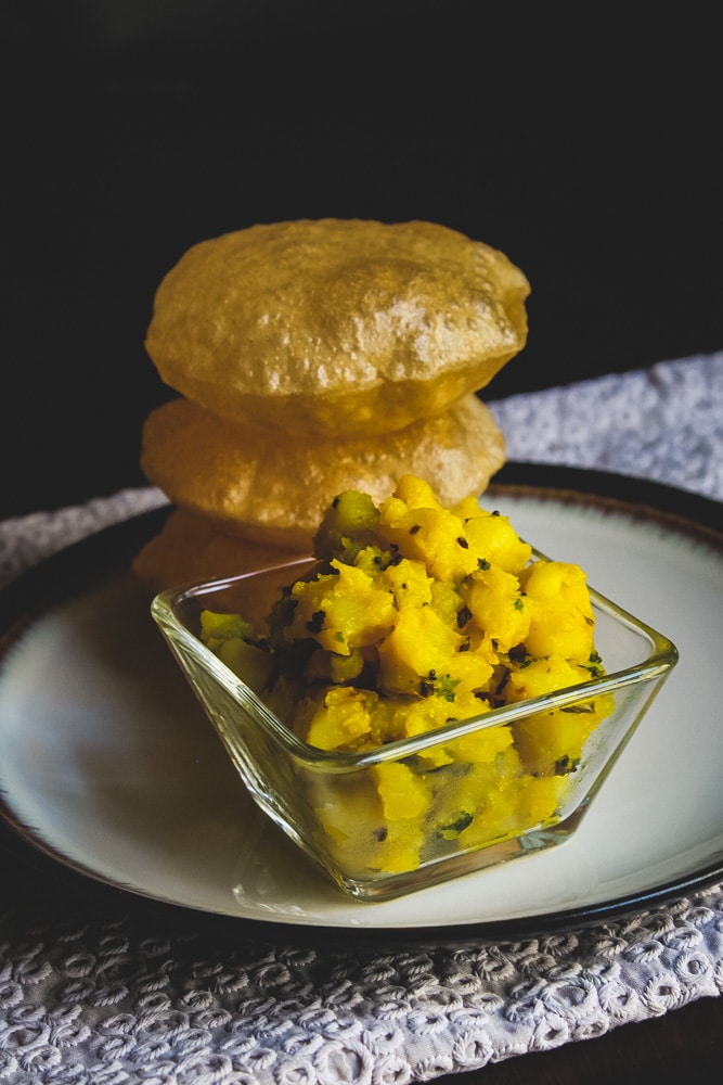 Bhaji served in a bowl and a stack of poori.