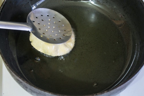 frying poori by gently pressing on top