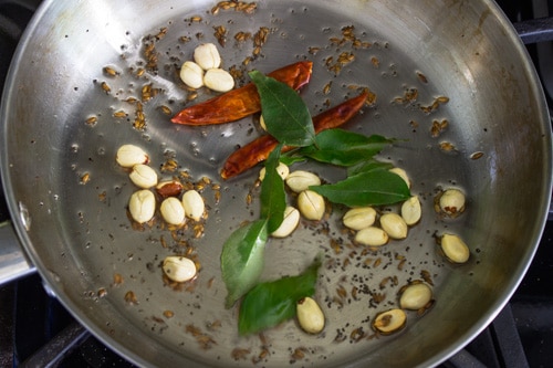 sauteing peanuts, curry leaves and dried red chilies