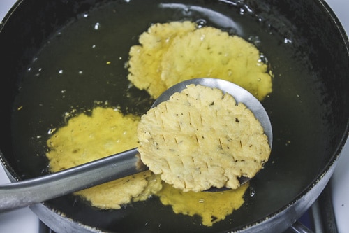 farsi puri is fried and removed using slotted spatula