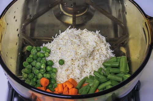 Soaked rice and veggies in a saucepan