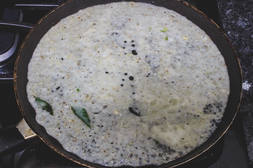 spreading dosa batter in a pan