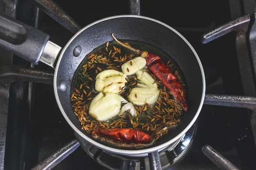 adding garlic cloves and dried chilies