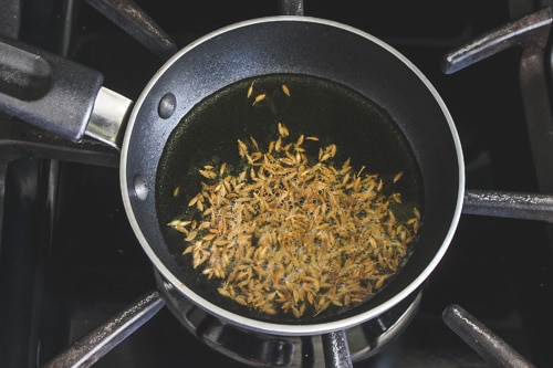 adding cumin seeds to the ghee