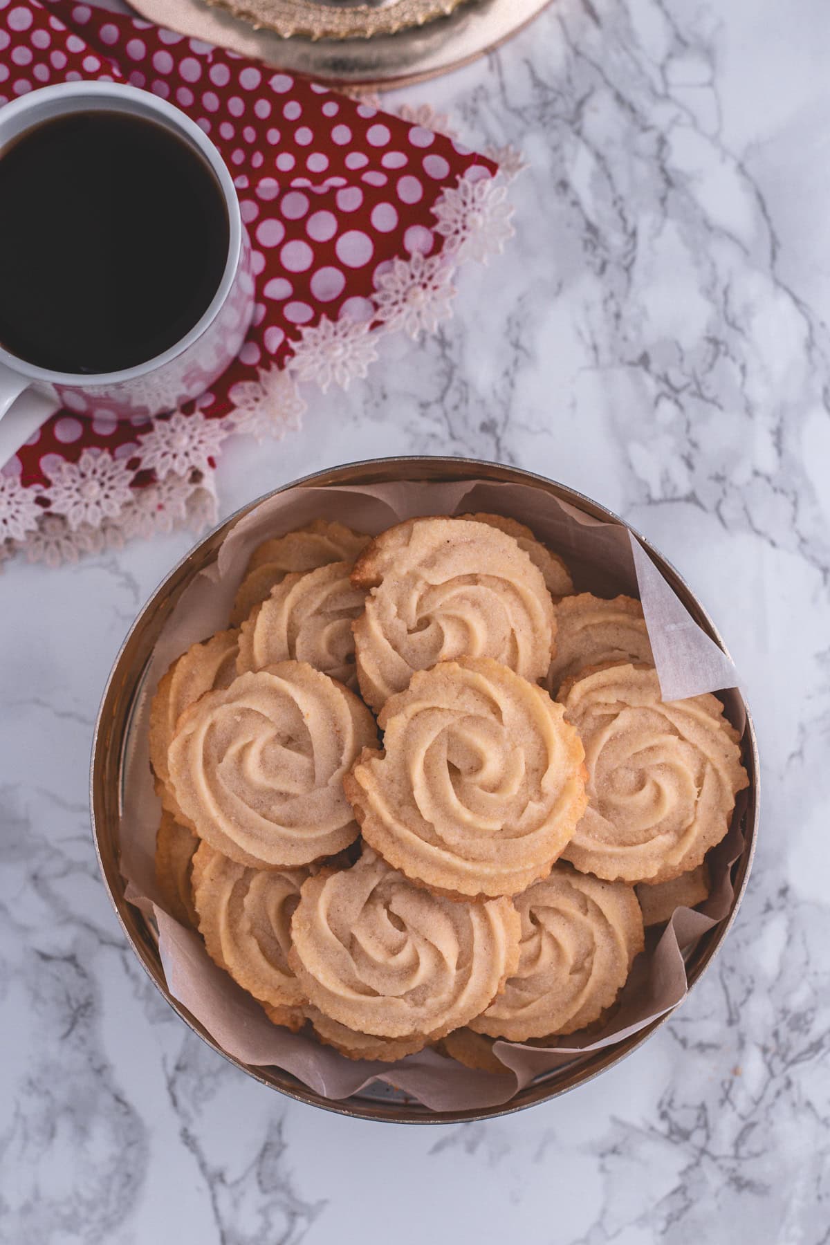 A container of eggless butter cookies with a cup of coffee.