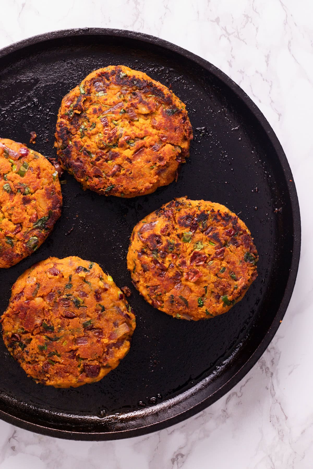 4 Kidney bean burger patties on a cast iron skillet.