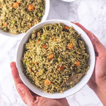 A bowl of palak rice holding with two hands and another bowl in the back.