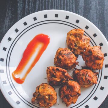 Dill leaves pakoda in a plate with ketchup on side