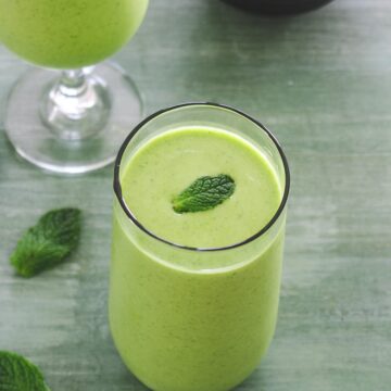 Mango mint smoothie in a glass with mint lead as a garnish