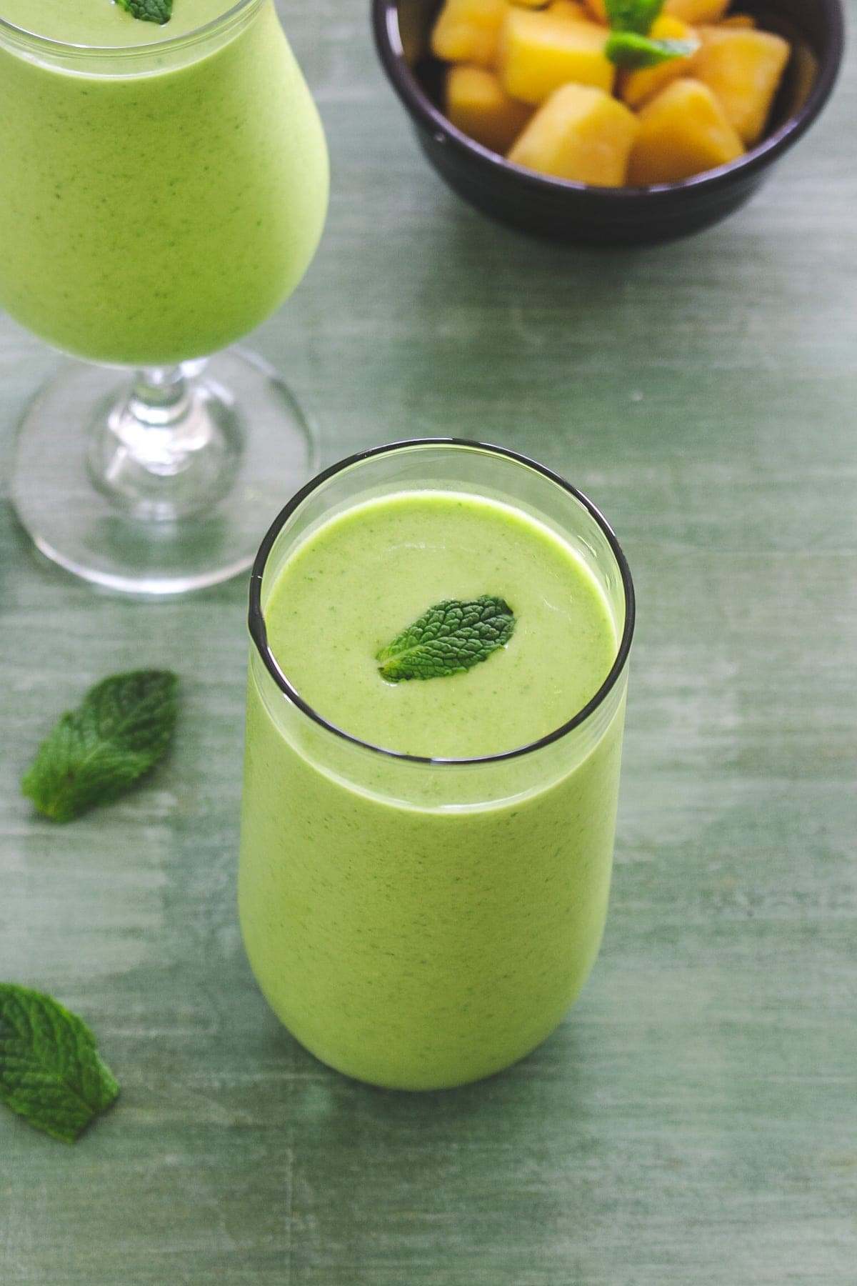 Mango mint smoothie in a glass with mint lead as a garnish