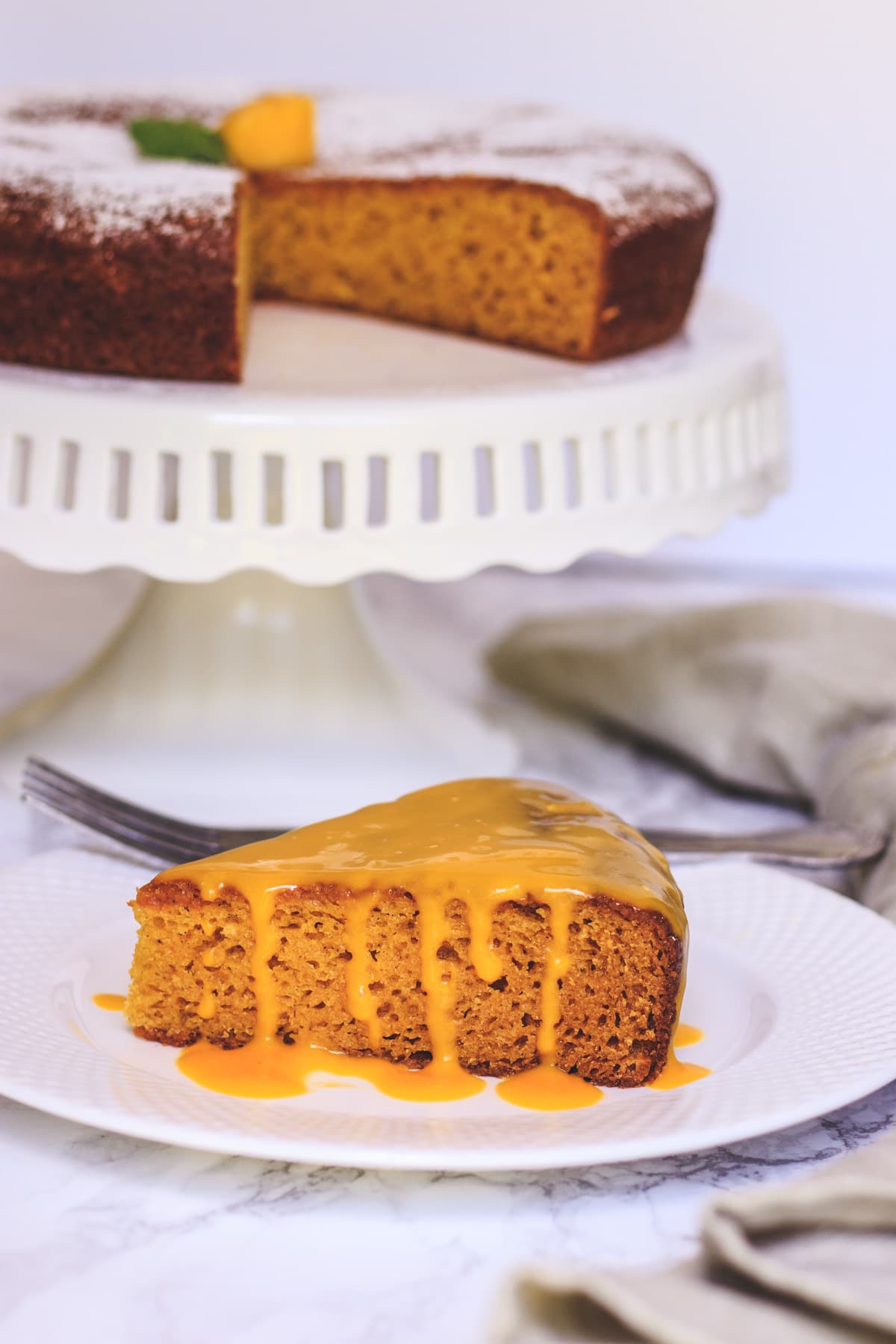 Slice of eggless mango cake with drizzle of mango sauce