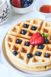 Close up shot of eggless waffles with toppings of berries and maple syrup