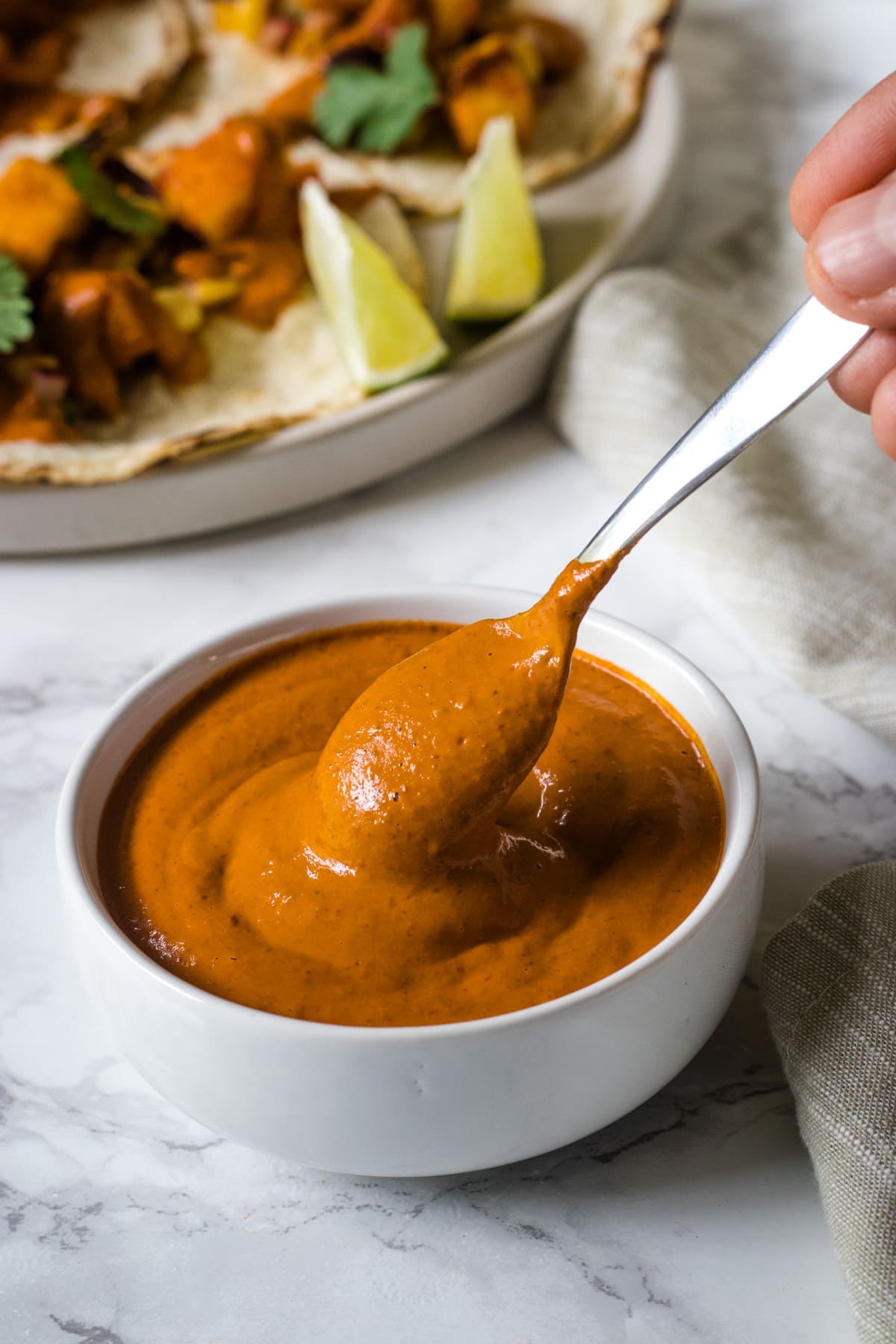 Image of chipotle sauce in a bowl with drizzle showing using small spoon.