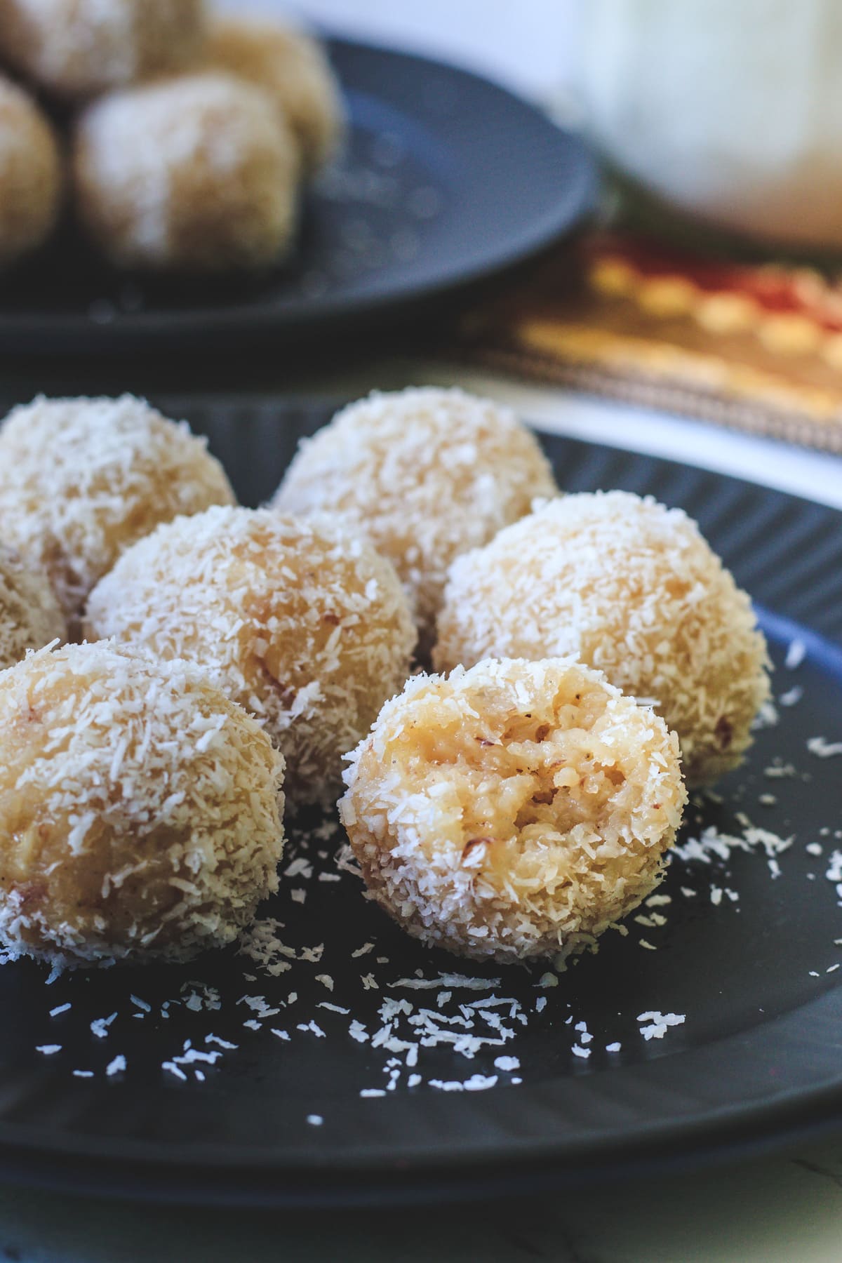 close up of coconut ladoo on the plate with one bite taken