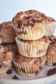 stack of eggless chocolate chip muffins on a plate with few chocolate chips on side