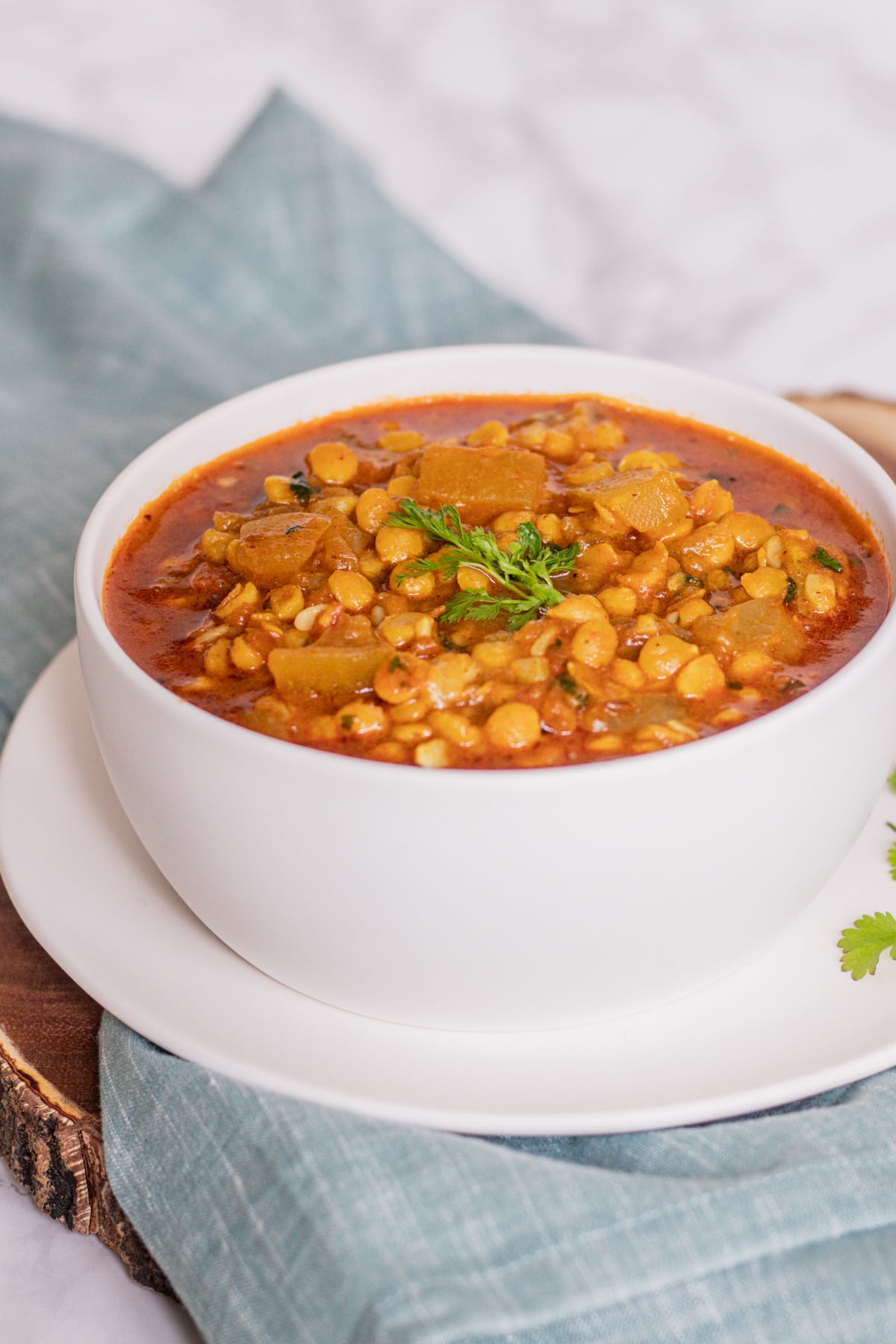 lauki chana dal in a bowl and a plate with a napkin underneath with garnish of cilantro