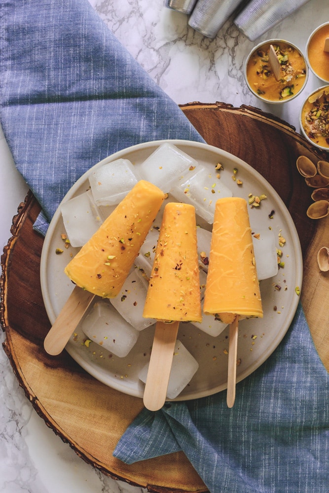 3 Mango Kulfi on ice cubes full of plate & napkin under it